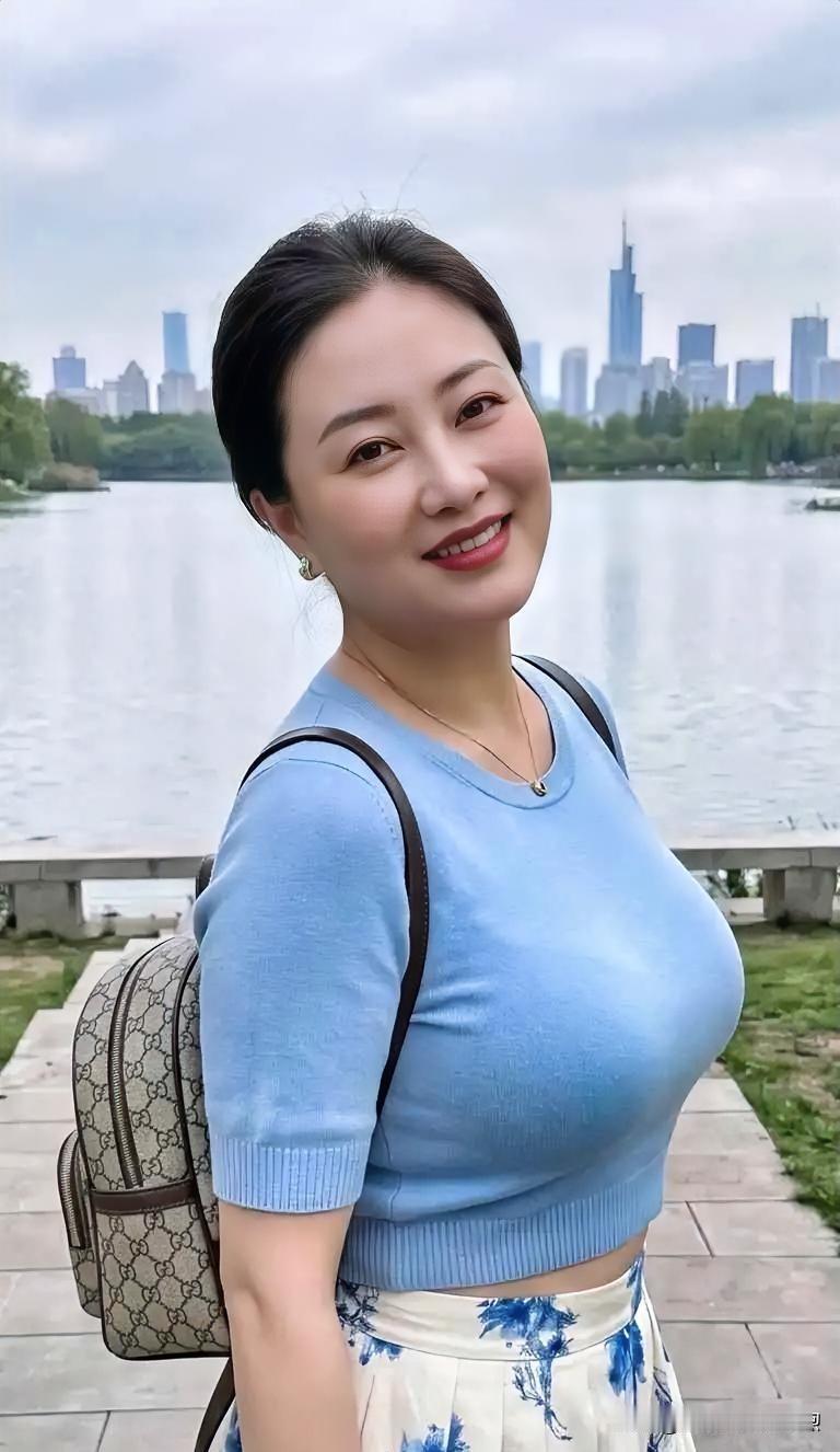 湖畔微风轻拂，浅蓝针织衫衬出温婉气质，笑意盈盈间，尽显都市女性的从容与柔美。