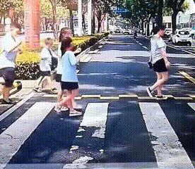 湖南，汽车司机停车为过马路的学生们让行。一个小男孩走过时，突然漂亮地转身跪下，给