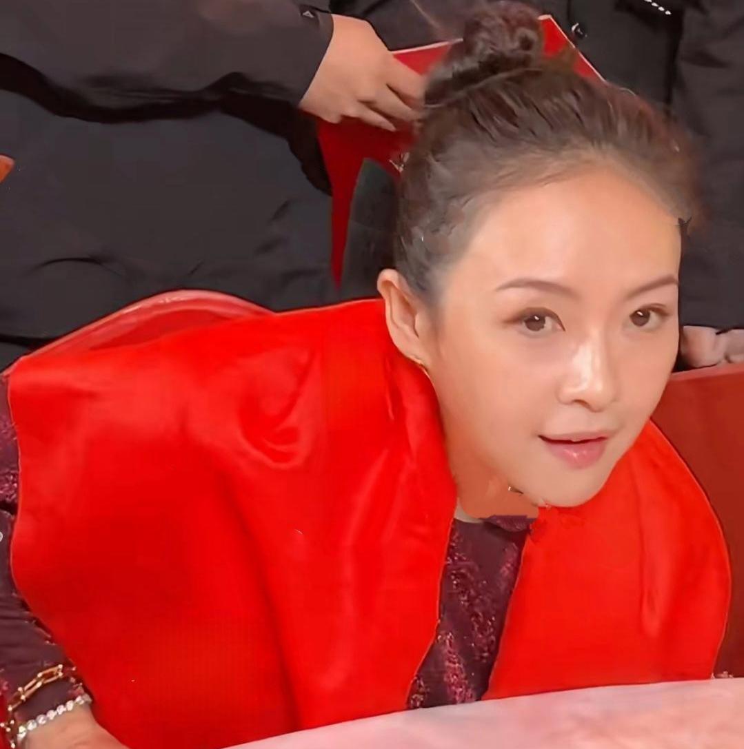 章子怡出席百花迎春晚会，身披中国红锦缎丝带，皮肤光滑水嫩，吹弹可破，高高扎起的丸
