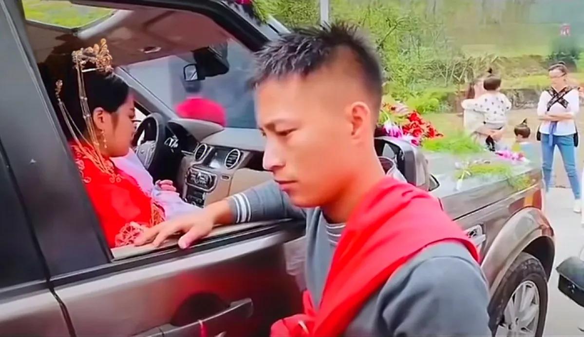 要下车钱！新娘板着脸，不给钱就不下车。一旁新郎的朋友塞给新郎一叠钱，新娘嫌少。新
