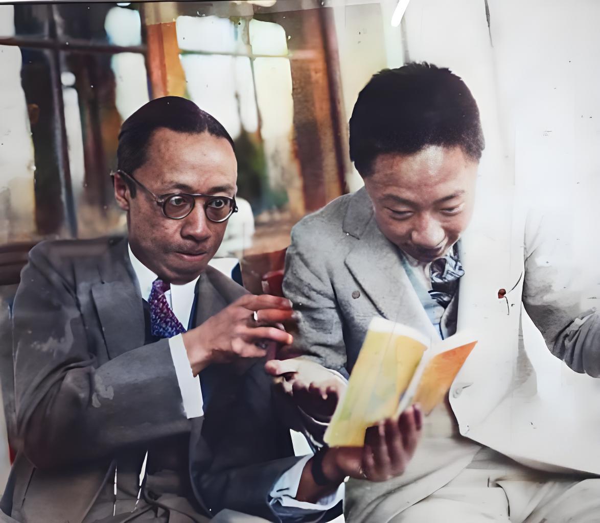 溥仪和他的兄弟溥杰同坐一处，都身着西装，氛围轻松。溥仪戴着眼镜，手指向书本，似在