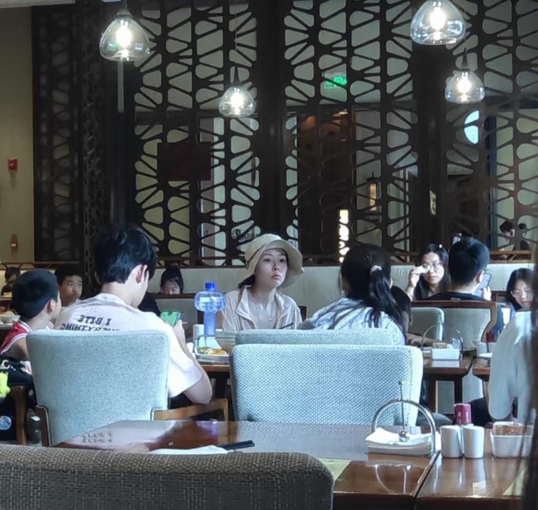 郭碧婷坐在西双版纳一家酒店大厅里吃饭，戴着帽子，素颜没有化妆，萌萌哒的表情