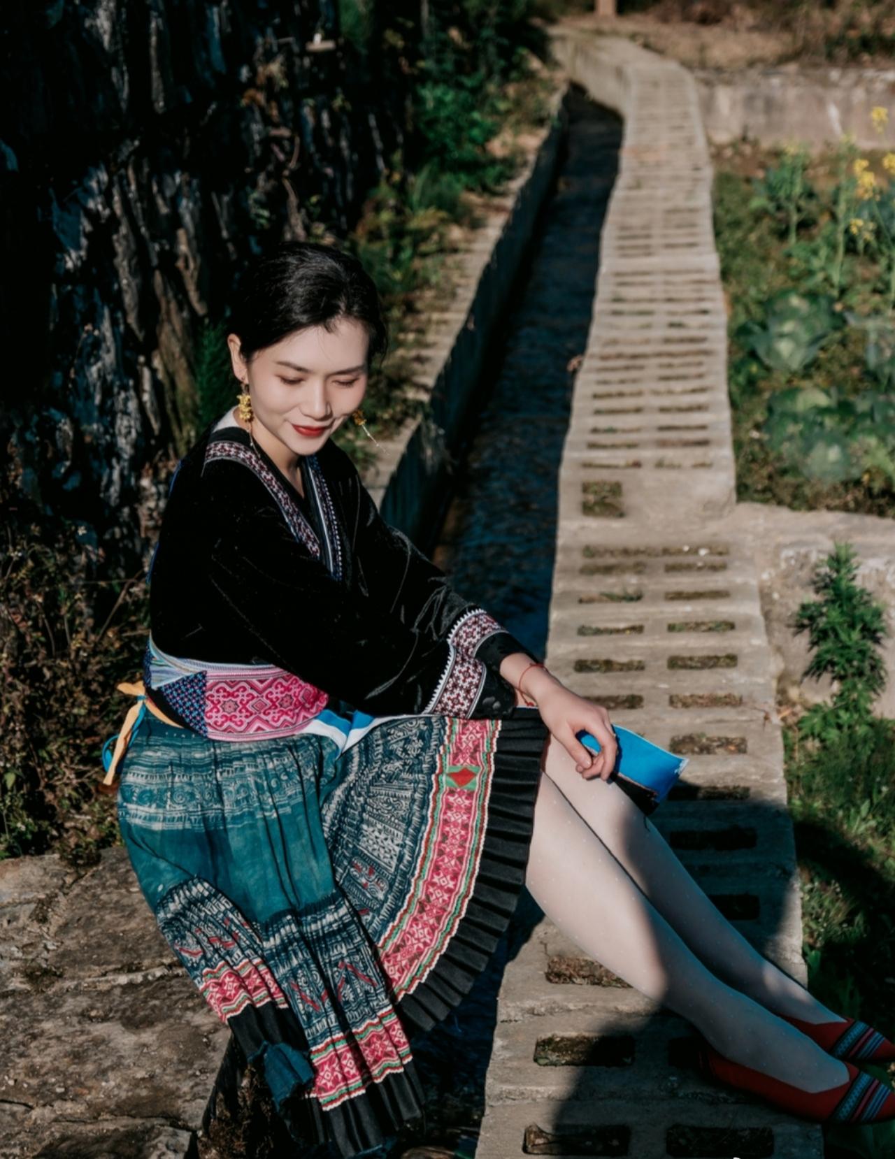 这套民族服饰在蓝天背景下太有“灵动民族风”的美感了！黑色底布搭配蓝粉撞色纹样，既