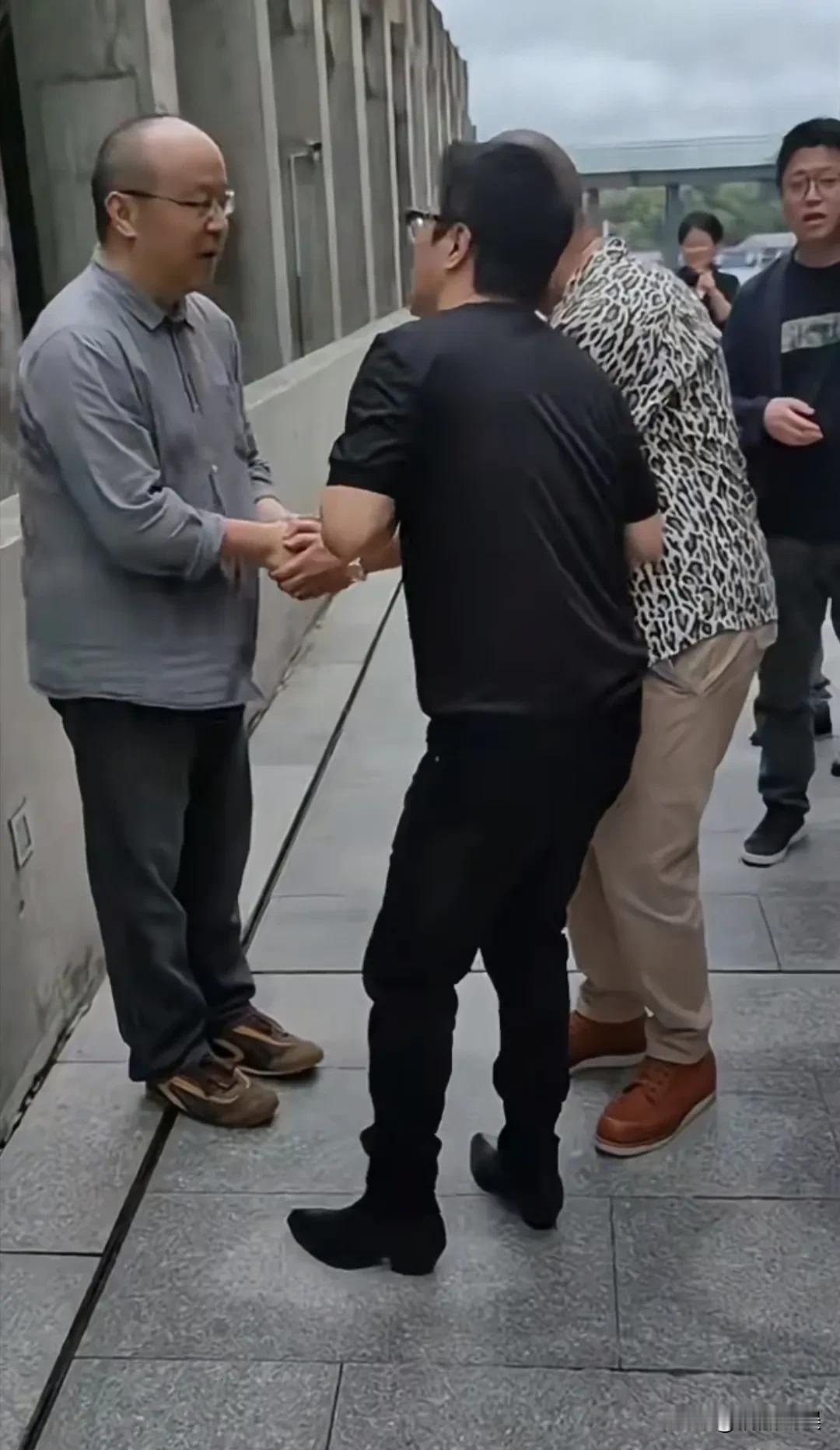 王菲前夫窦唯在阿那亚被人偶遇，遇到热情的粉丝，虽说握着手，但是一脸的拘谨不是假的