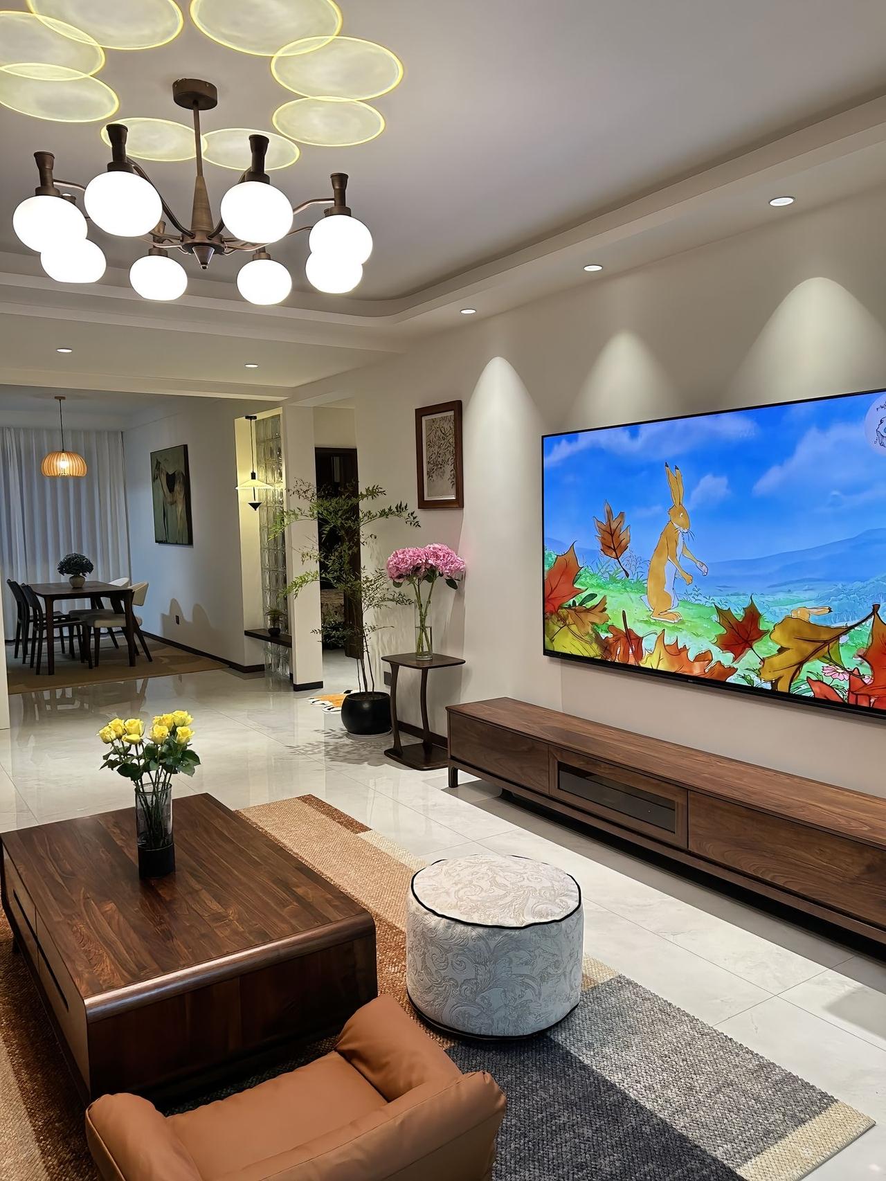 我家客厅风格温馨雅致,以胡桃木家具营造自然质感,电视墙的卡通画面增添活力,灯光设