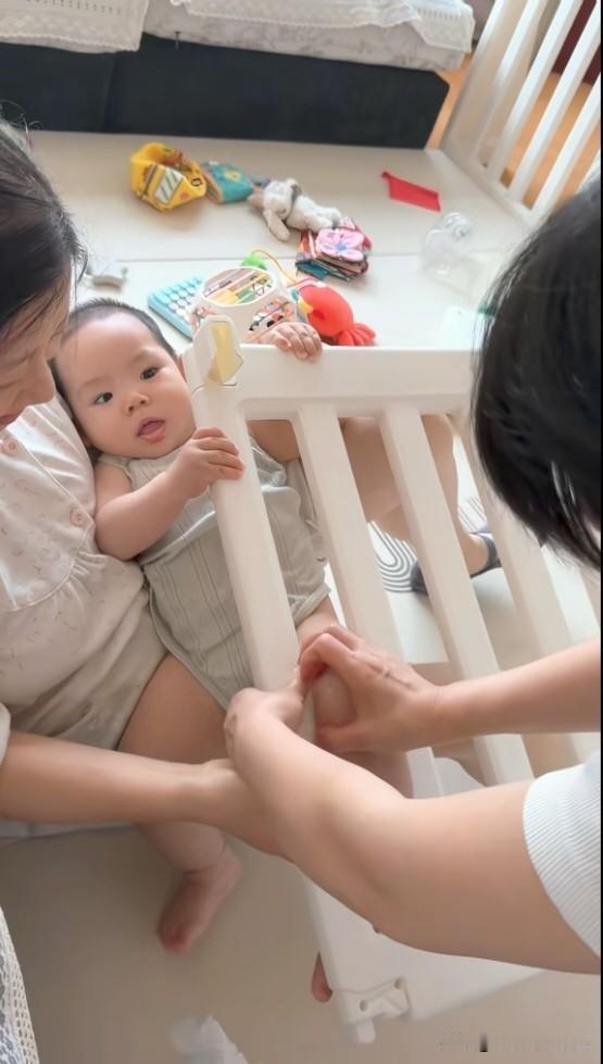 瞧这一幕，妈妈心都揪碎了。两个月大的小萌娃，不知怎的把腿卡在围栏里。妈妈和奶奶费