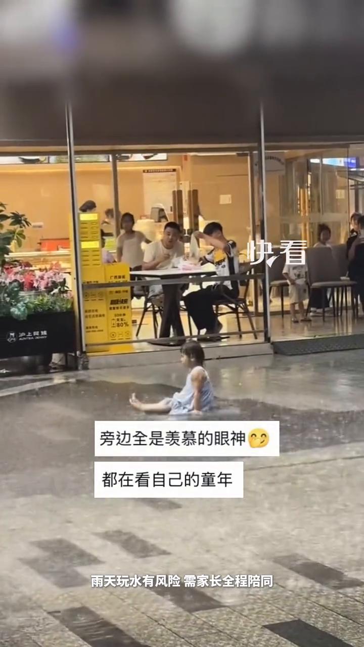 赤脚淋雨打滚萌娃雨中尽情撒欢。网友：她在雨中起舞。近日广西南宁，雨天玩水有风险