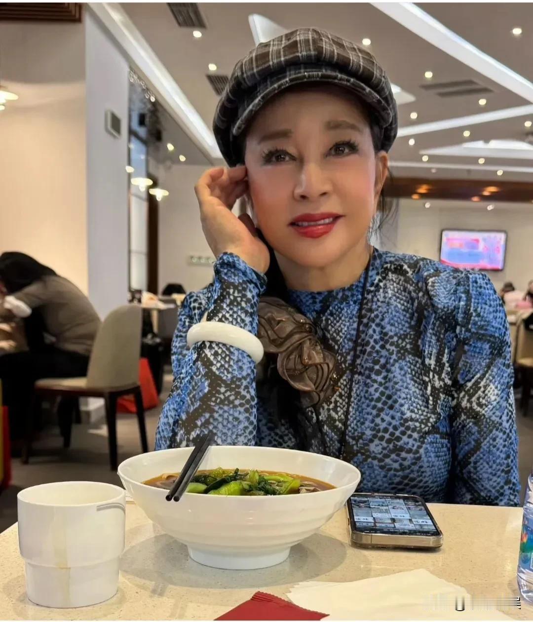 75岁的刘晓庆，与好友现身餐厅聚餐，戴着一顶格子贝雷帽，身穿蓝色紧身衣，胳膊上戴