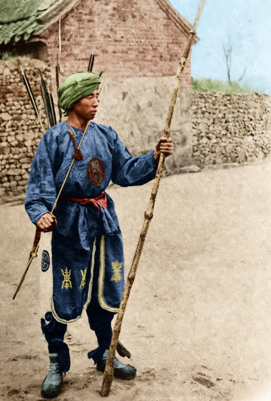 这张照片定格的是晚清义和团拳民，拳民裹着旧布头巾，身上的粗布短褂满是褶皱，背后箭