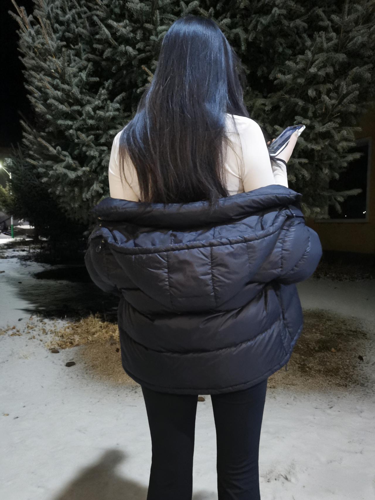 羽绒披得冬风软，长发垂成墨色流。雪径独行灯影里，一身清寂惹闲愁。