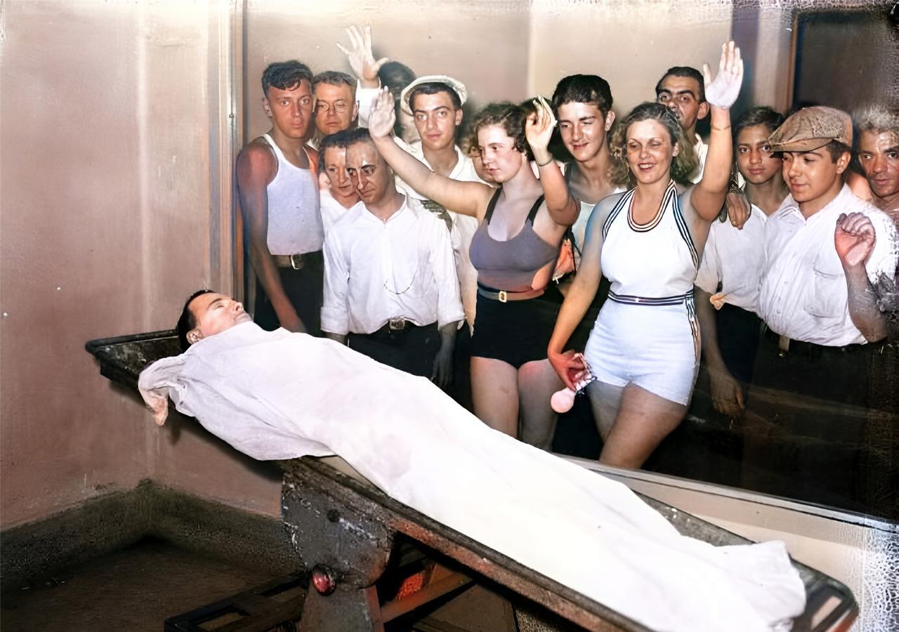 这是1934年7月22日，美国芝加哥的民众们隔着一层玻璃笑着观看一具尸体。这具尸