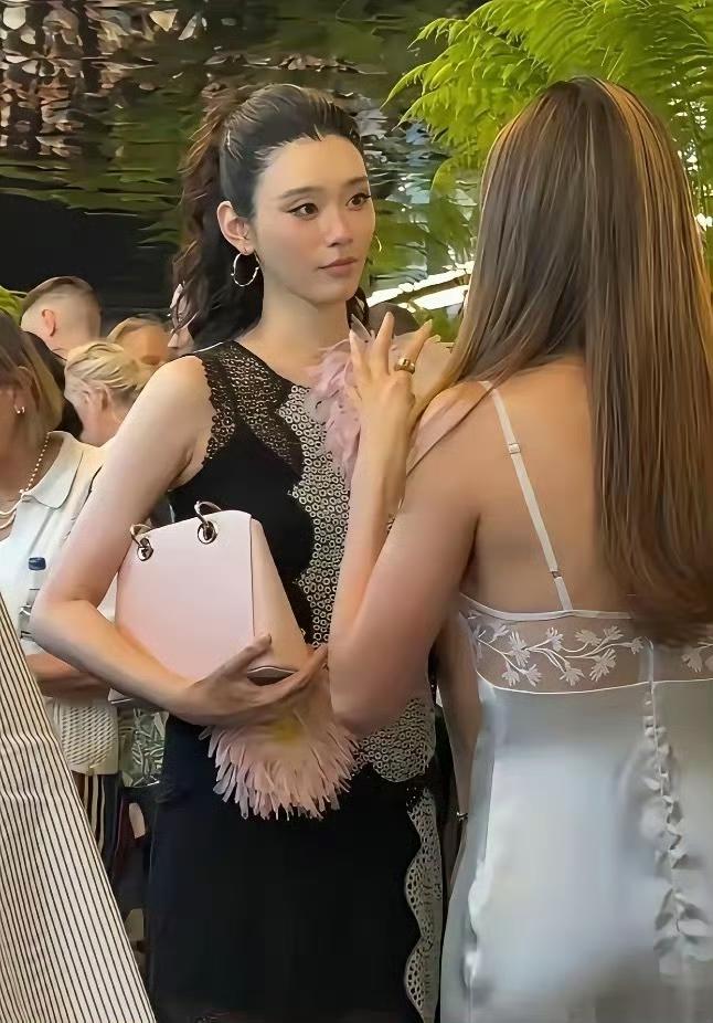奚梦瑶操作太绝了：前排与谷爱凌热聊时，余光瞥见镜头，右手瞬间拎起迪奥包，商标精准