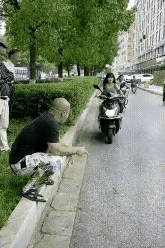 一位大爷蹲在路边等着碰瓷，看到一个美女骑着电动车过来，急忙起身躺在女孩车前，一手