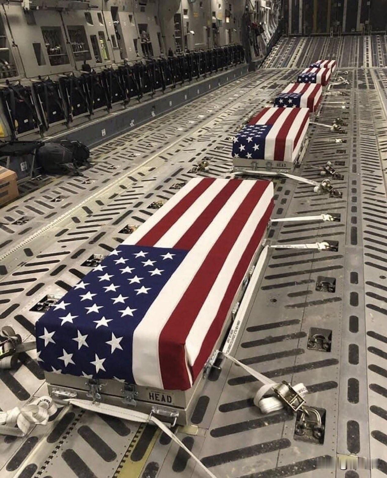 这张图片展示了覆盖着美国国旗的灵柩，它们位于一架军用运输机（可能是C-17“环
