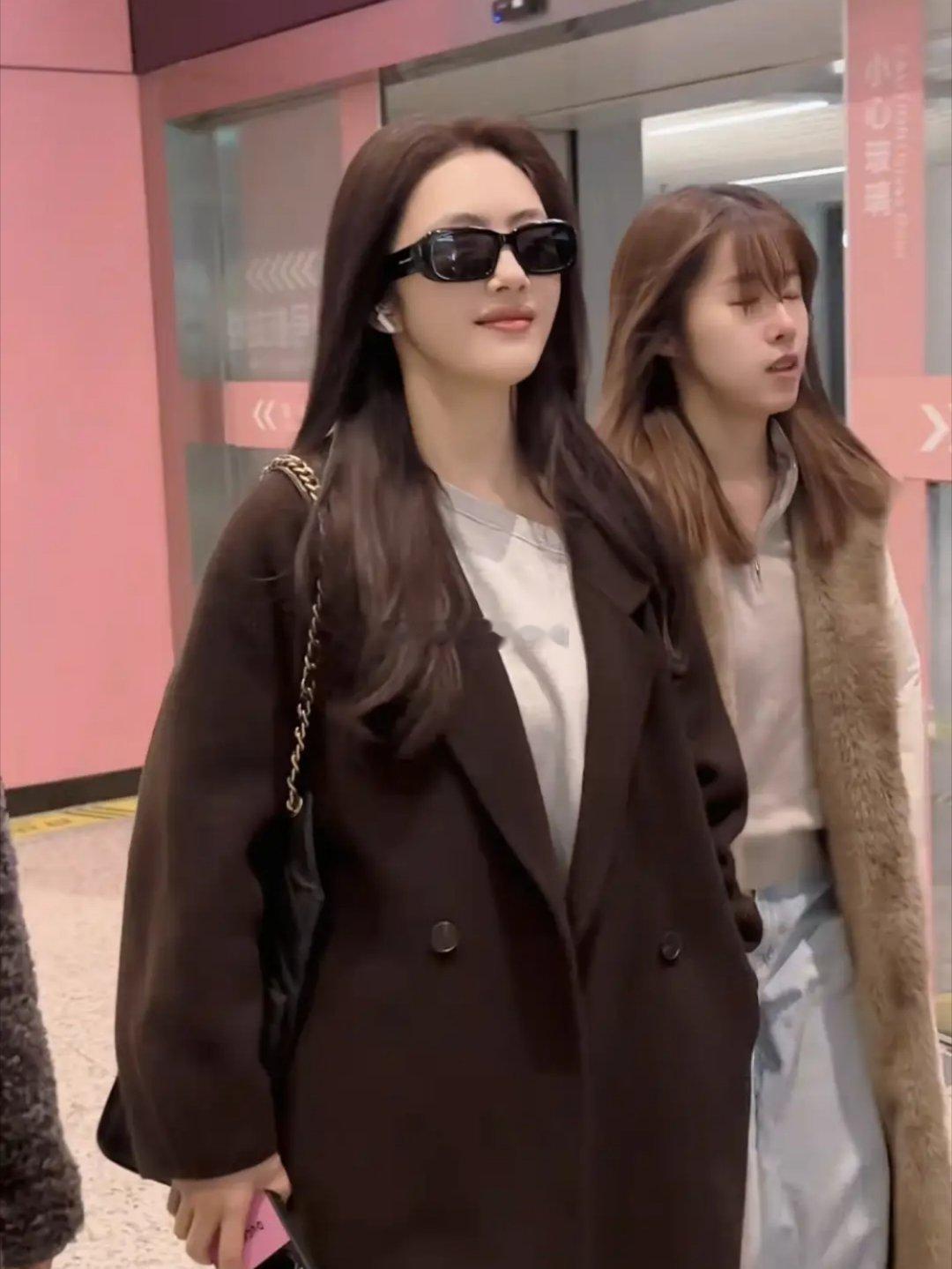 蔡文静机场造型亮眼，大衣配短裙靴子飒气十足，肌肤白皙透亮，状态绝佳，行走间气场全