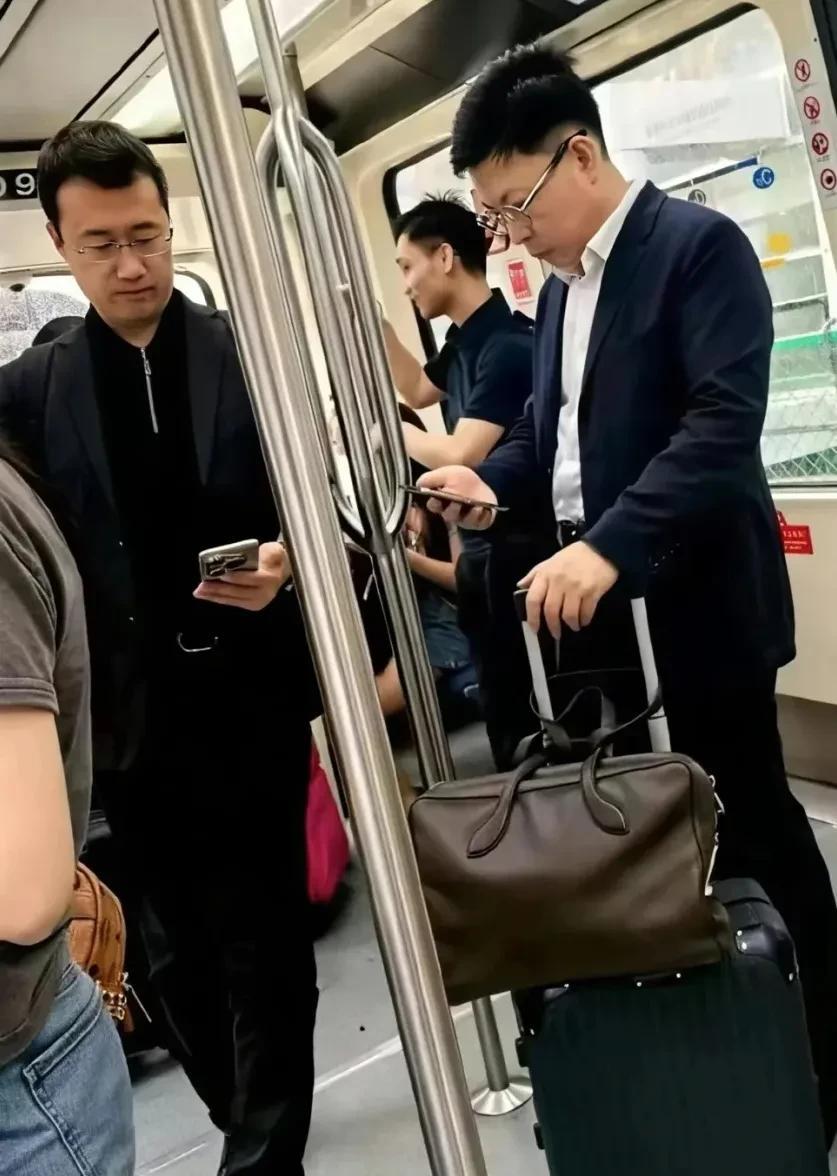 网友在机场摆渡车上偶遇何刚和余承东，俩人都在专注看手机。这俩人出差风格不一样，