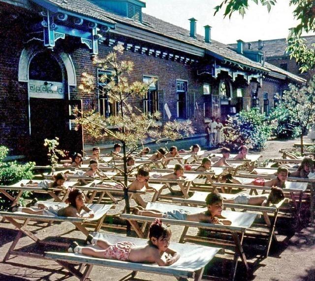 这是1959年沈阳工人新村幼儿园的娃娃们穿着裤衩躺在院子里各自的小床上享受日光浴