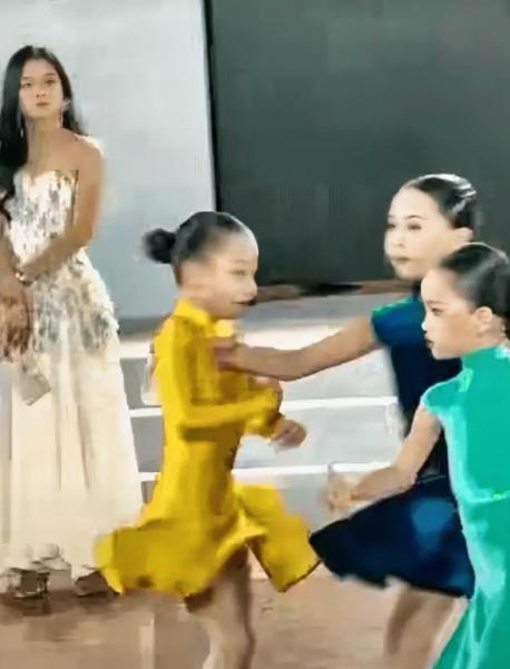 小小年纪就心思不正。深圳拉丁舞大赛现场，身着黄裙子的女孩正专注投入地跳舞，蓝裙子