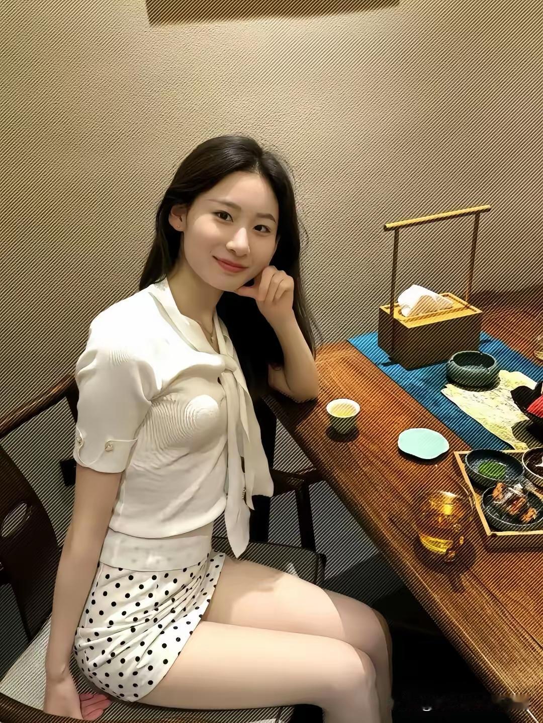 一位女生坐在餐桌旁，微笑着看镜头。如何给女友拍性感和可爱的照片穿牛仔短裤拍照,