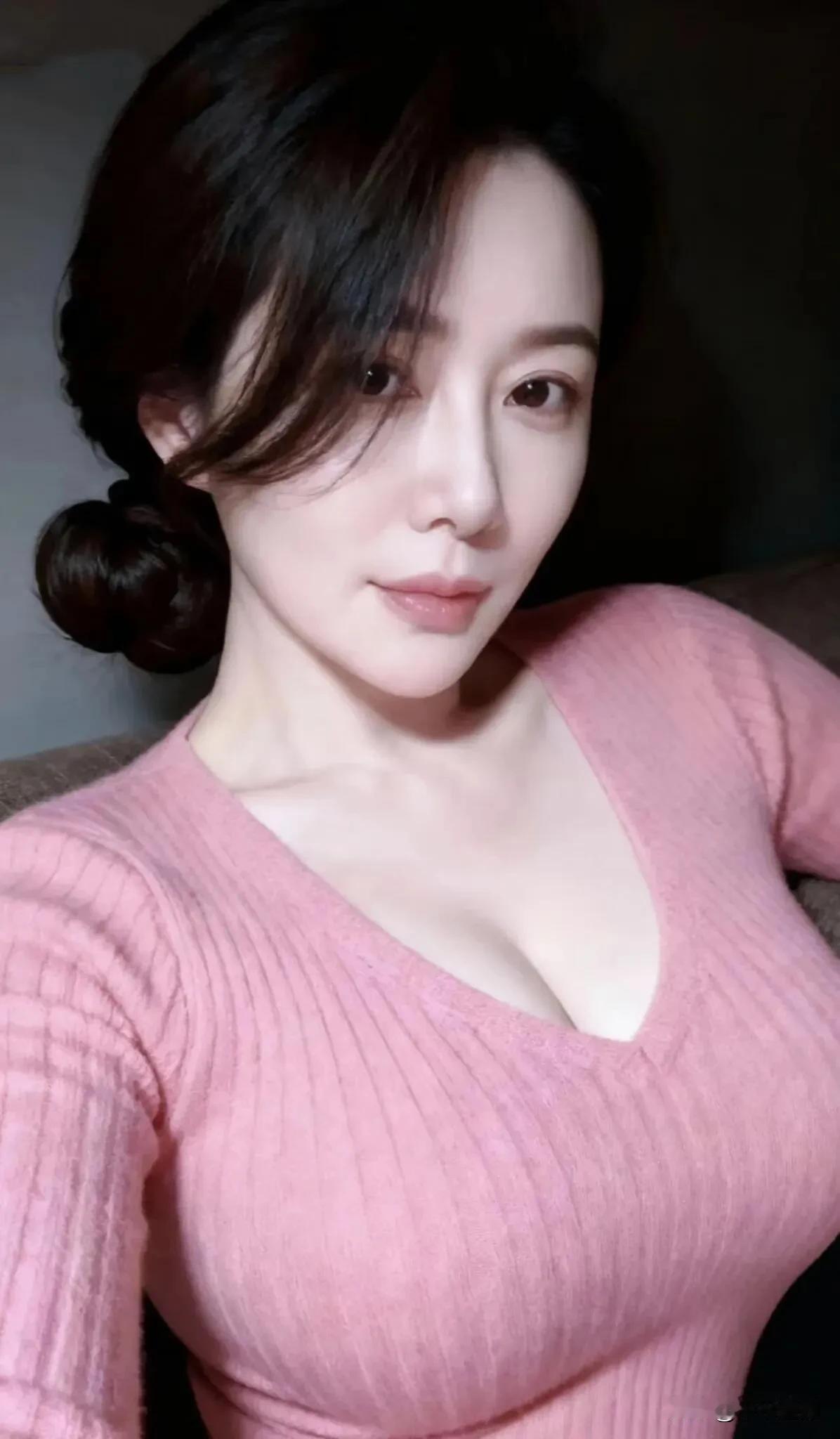 粉调针织衫裹着柔糯质感，低领设计衬出纤薄肩颈。慵懒盘发垂落耳侧，在暗调氛围里，把