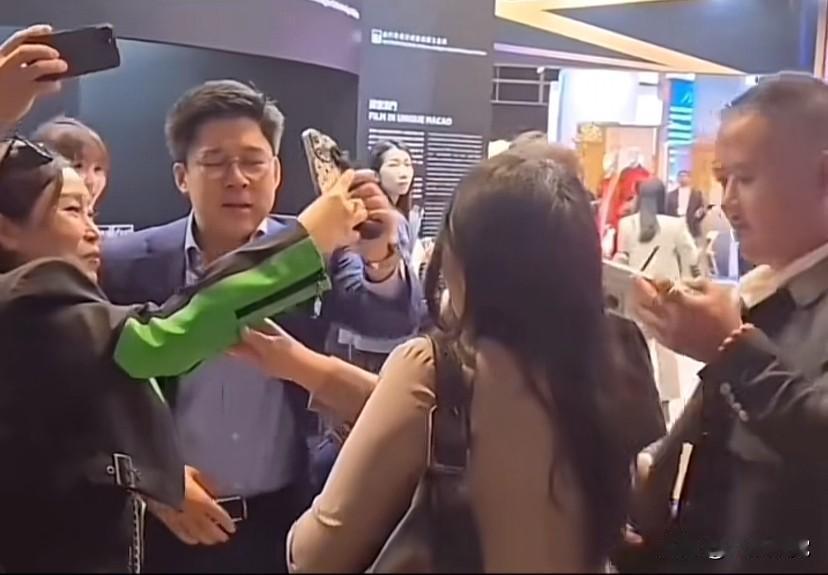 香港霍家三代霍启刚和两个女同事在商场里走着，一群人围上来要拍合影，拍了几张后，霍