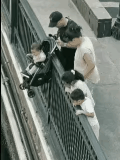 一家六口来到海边看风景，坐在婴儿车上的小男孩看见大海后非常的开心。于是，父母把婴
