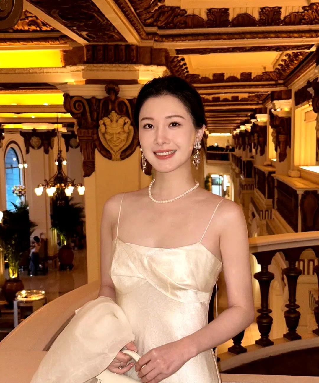 欧根纱晕开朦胧诗意，缎面裙裹住流金光泽，珍珠项链轻绕颈间，将温润与矜贵揉成一团。