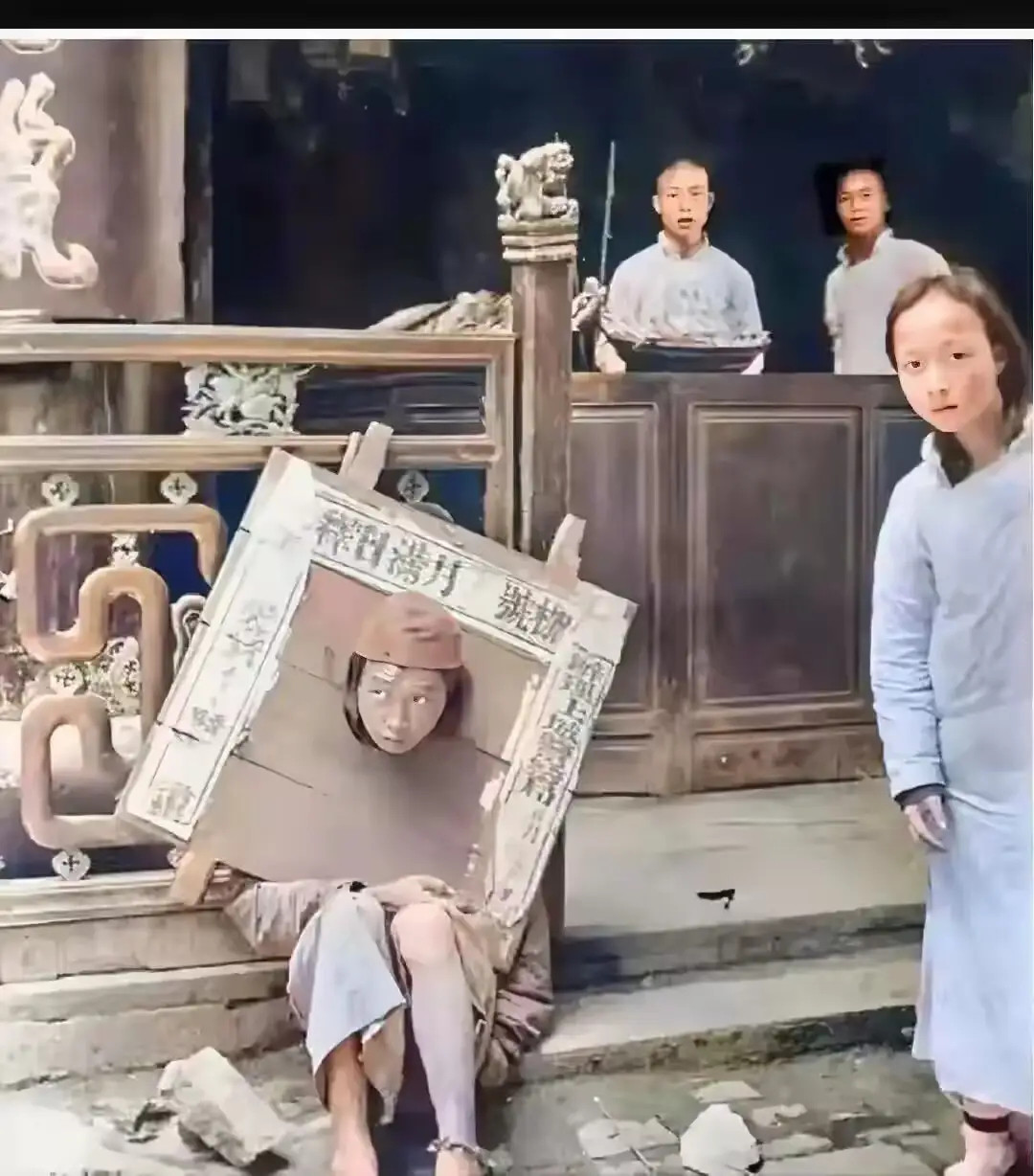 1908年，清末时期，上海街头，一名戴着“木枷”的犯人，正坐在台阶上休息，镜头中