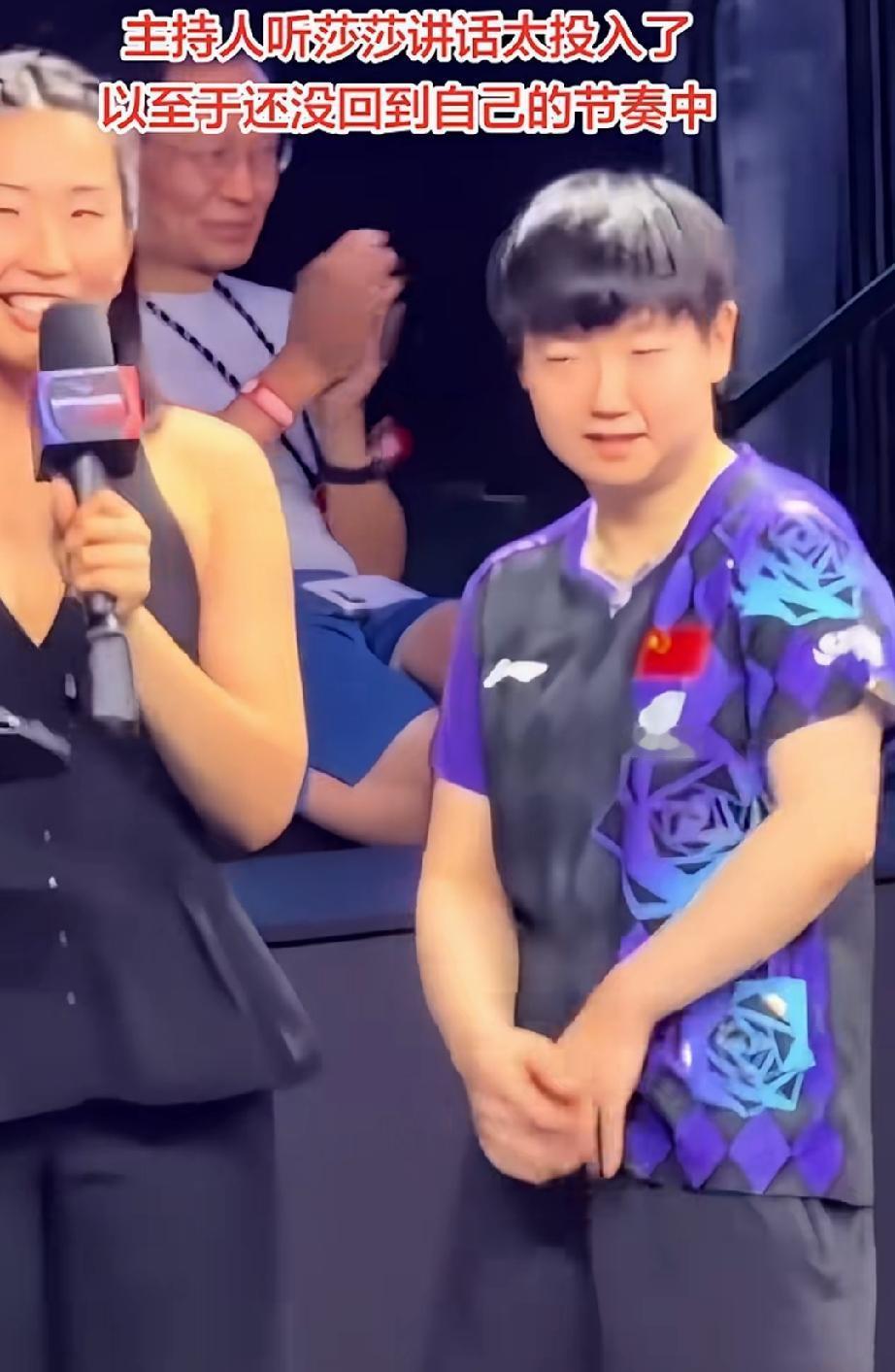 注意到莎莎单打结束，接受采访，后面有位男士很突出。穿着短裤，戴着珠子。他本来看着