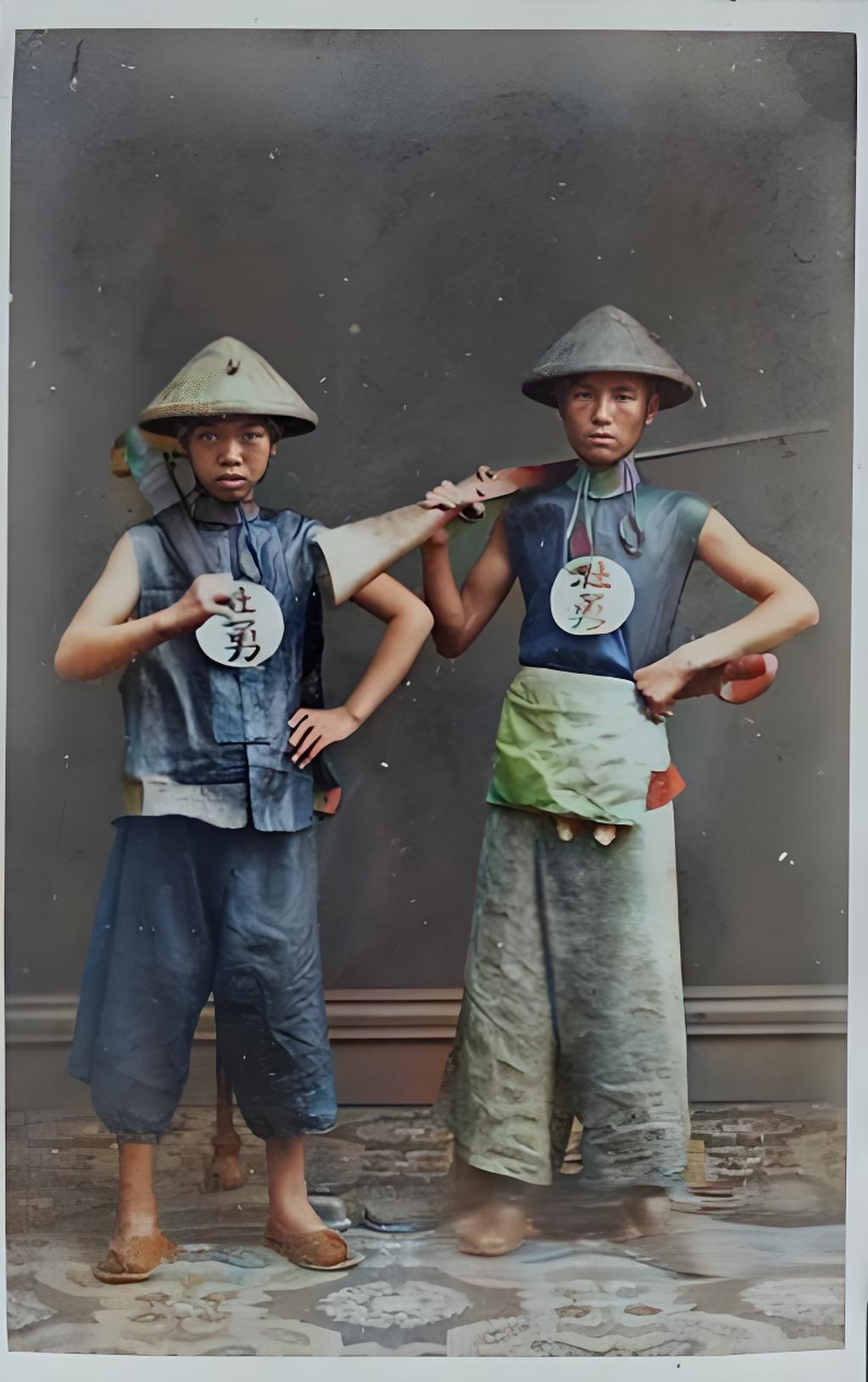这是晚清时期的老照片，展示的是两名“壮勇”形象。他们头戴斗笠，身着简易服装，胸前