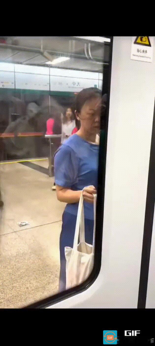女子没有赶上地铁，她不慌不忙地站屏蔽门边，用手提袋挡着屏蔽门，屏蔽门感应到有物体