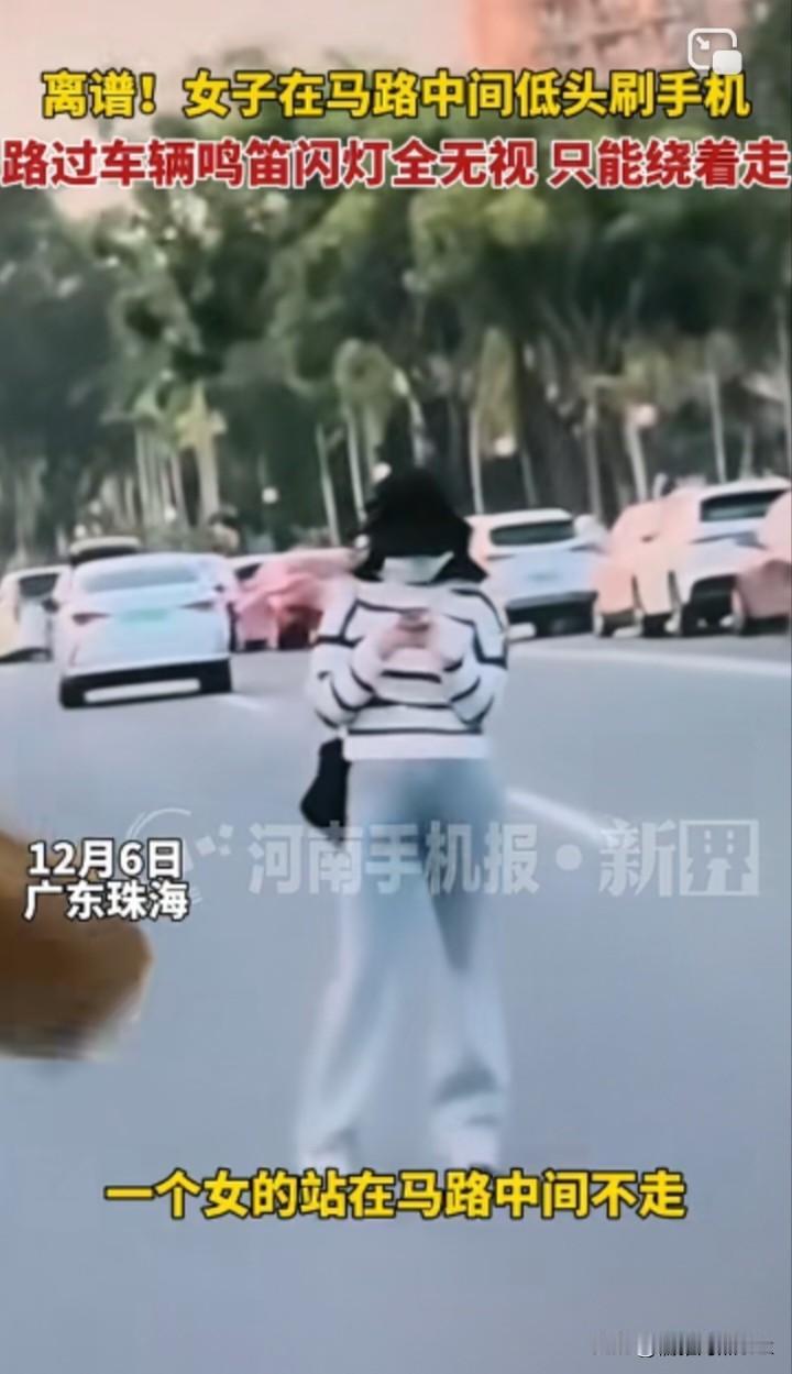 这种女人得治！女子站在马路中间低头刷手机，路过车辆呜笛闪灯全无视，纷纷绕路走。网