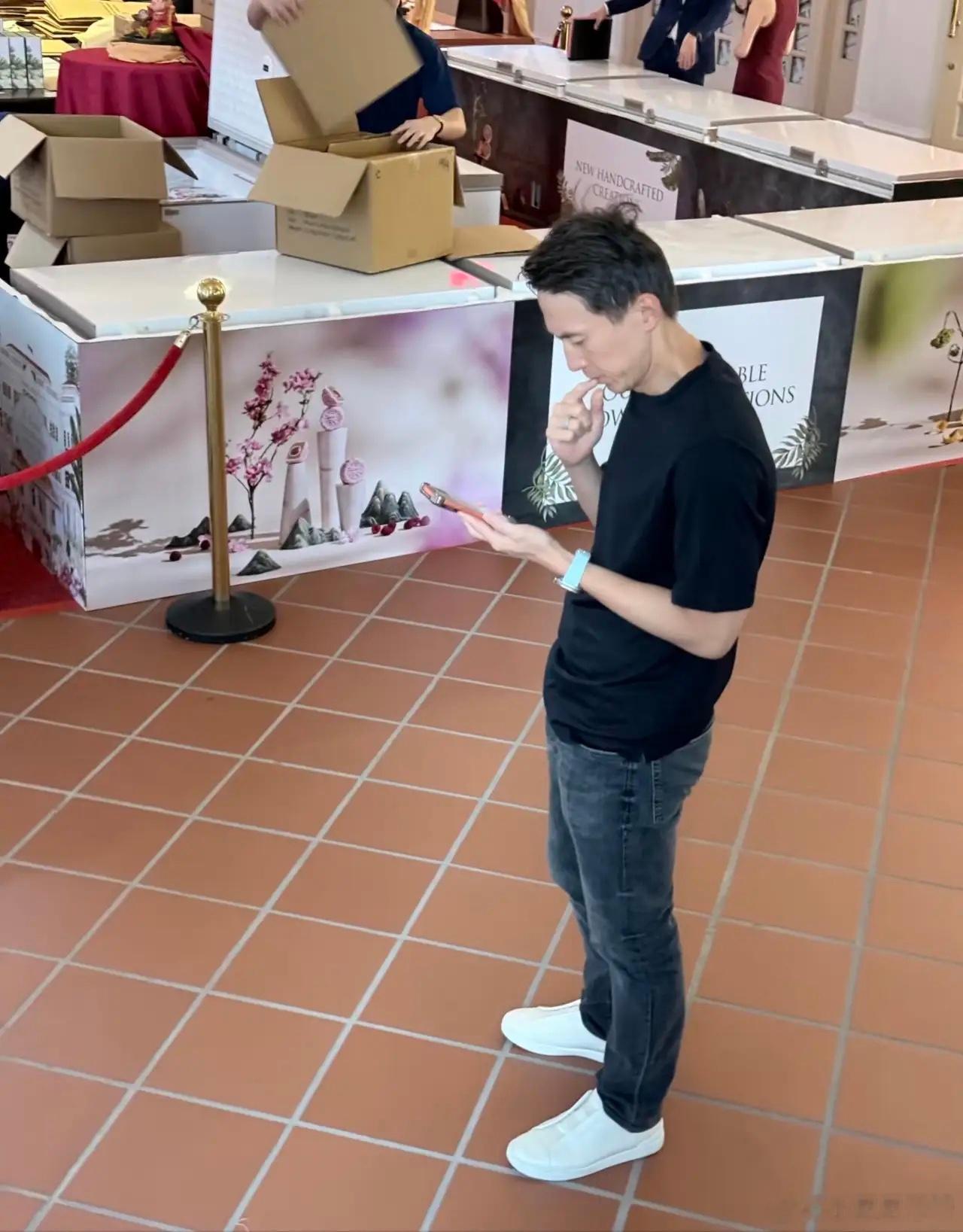 43岁TikTok总裁周受资在新加坡一间酒店大堂被偶遇，他站在过道上看手机，时不