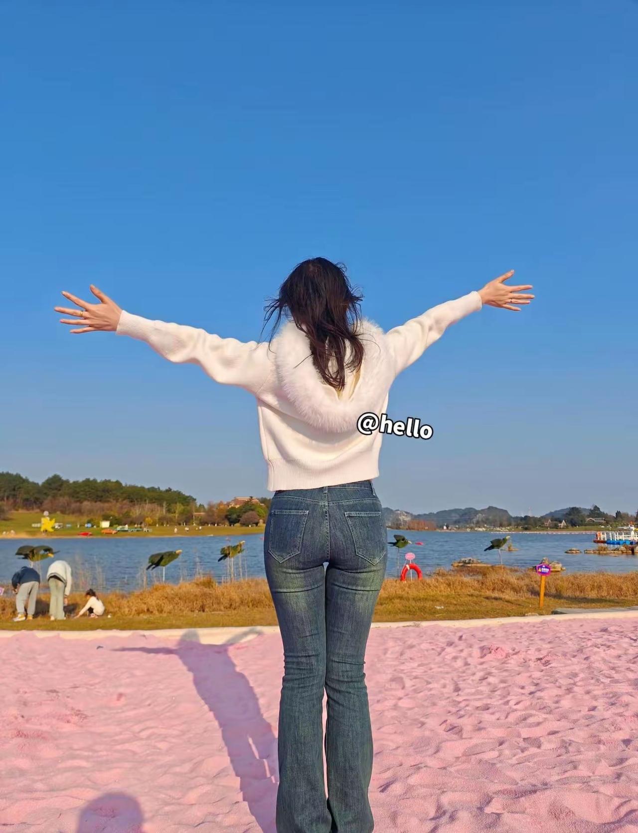 在湖边，背对镜头，天空晴朗。