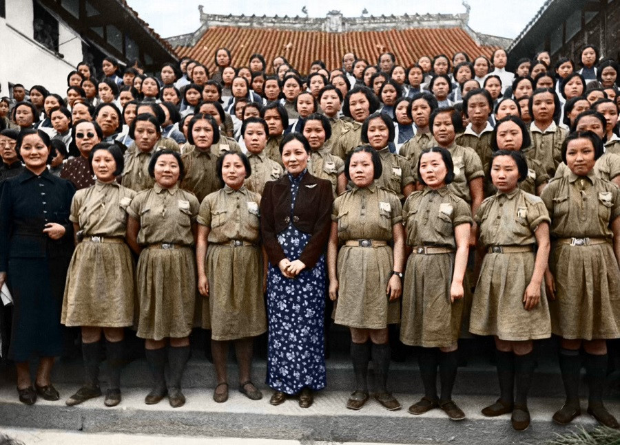 1943年，宋美龄到访一所孤儿院，与身着统一制服的女学生们合影。她身着旗袍外搭深