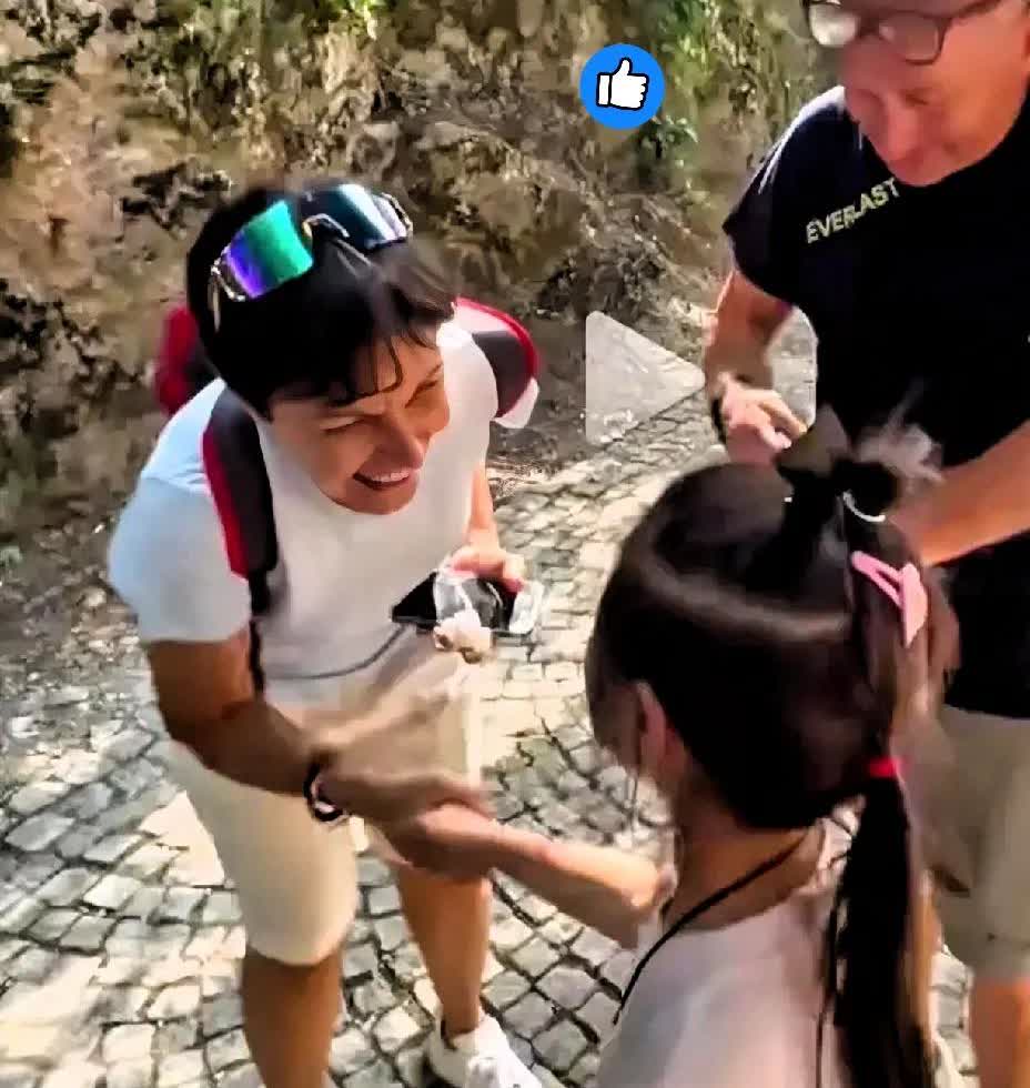 两意大利游客在中国游玩丢了手机，被一小姑娘捡到，小姑娘就站在原地等他们。游客拿回