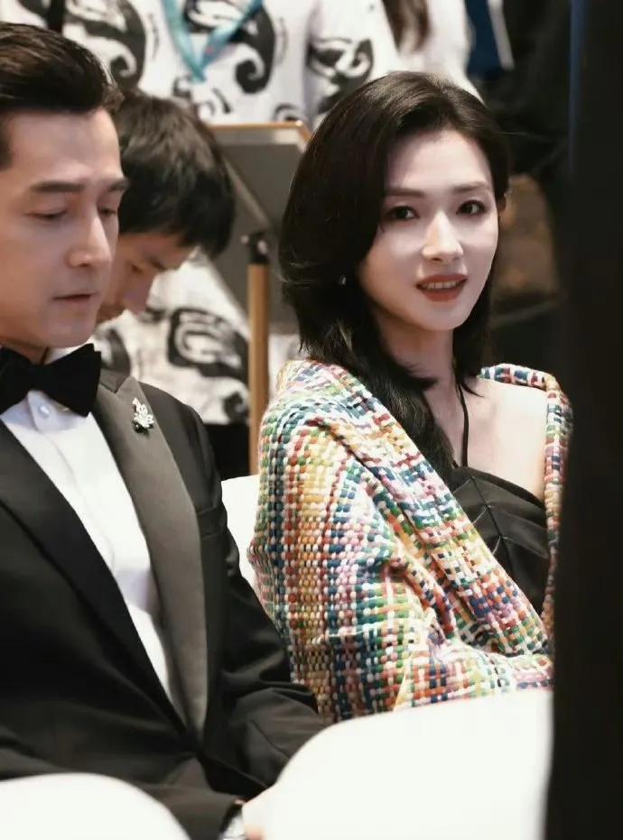 胡歌向万茜展示女儿的照片，万茜一边欣赏一边小心地用手遮挡，以防被无意间拍摄。