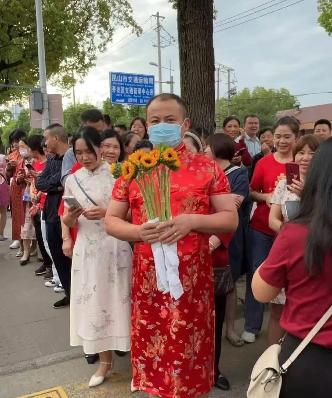 高考着装再升级，从妈妈穿旗袍，举甘蔗，改为爸爸穿旗袍，穿紫色内裤。现在又升级为