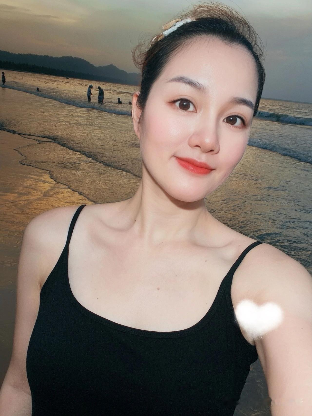 在海滩上自拍，背景是夕阳。