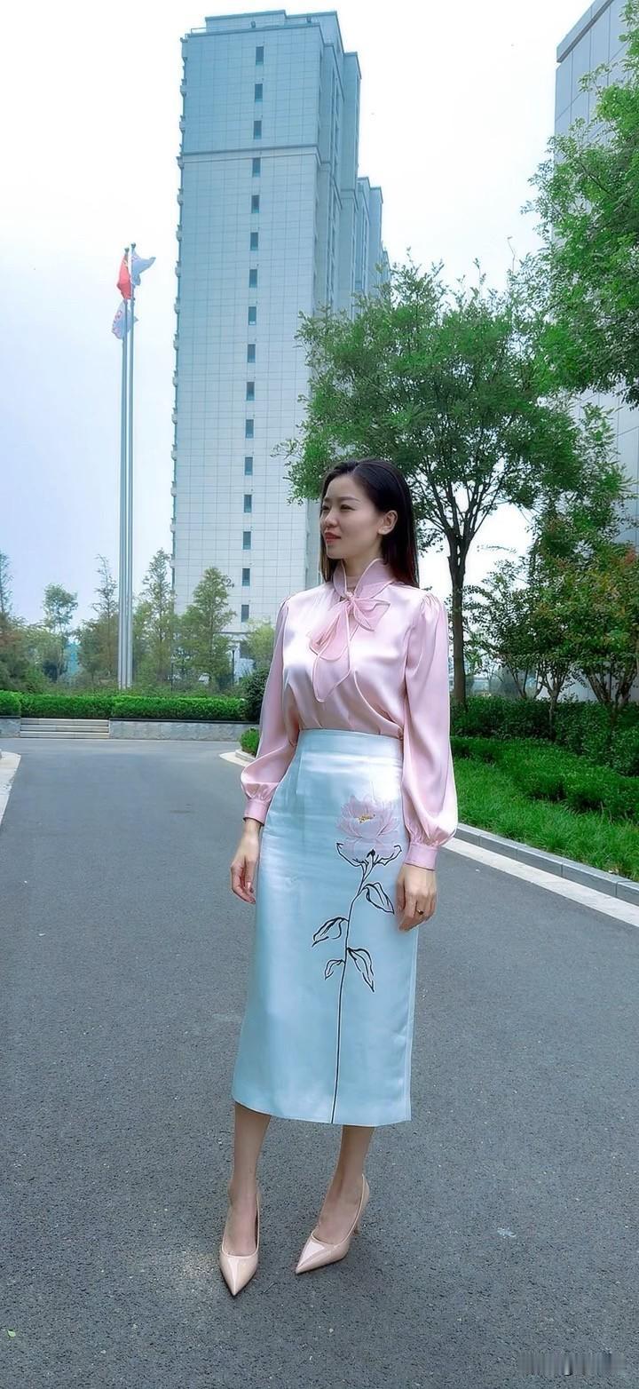 一个穿粉色连衣裙的女士站在路上。