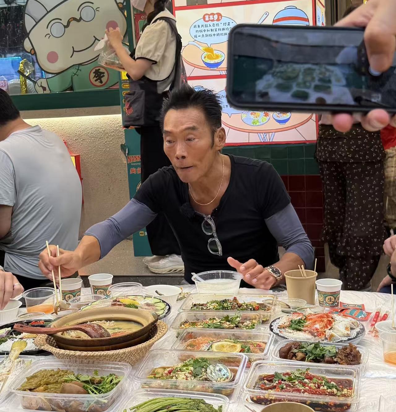 62岁港星郑浩南现身广东汕头一家餐馆吃生腌菜，他坐在街边排队，点了一大桌海鲜，在