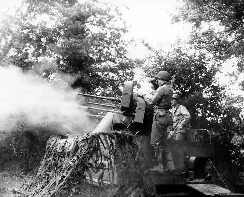 1944年7月12日，驻扎在法国的美军第377防空部队的士兵们正在用火炮支援步兵