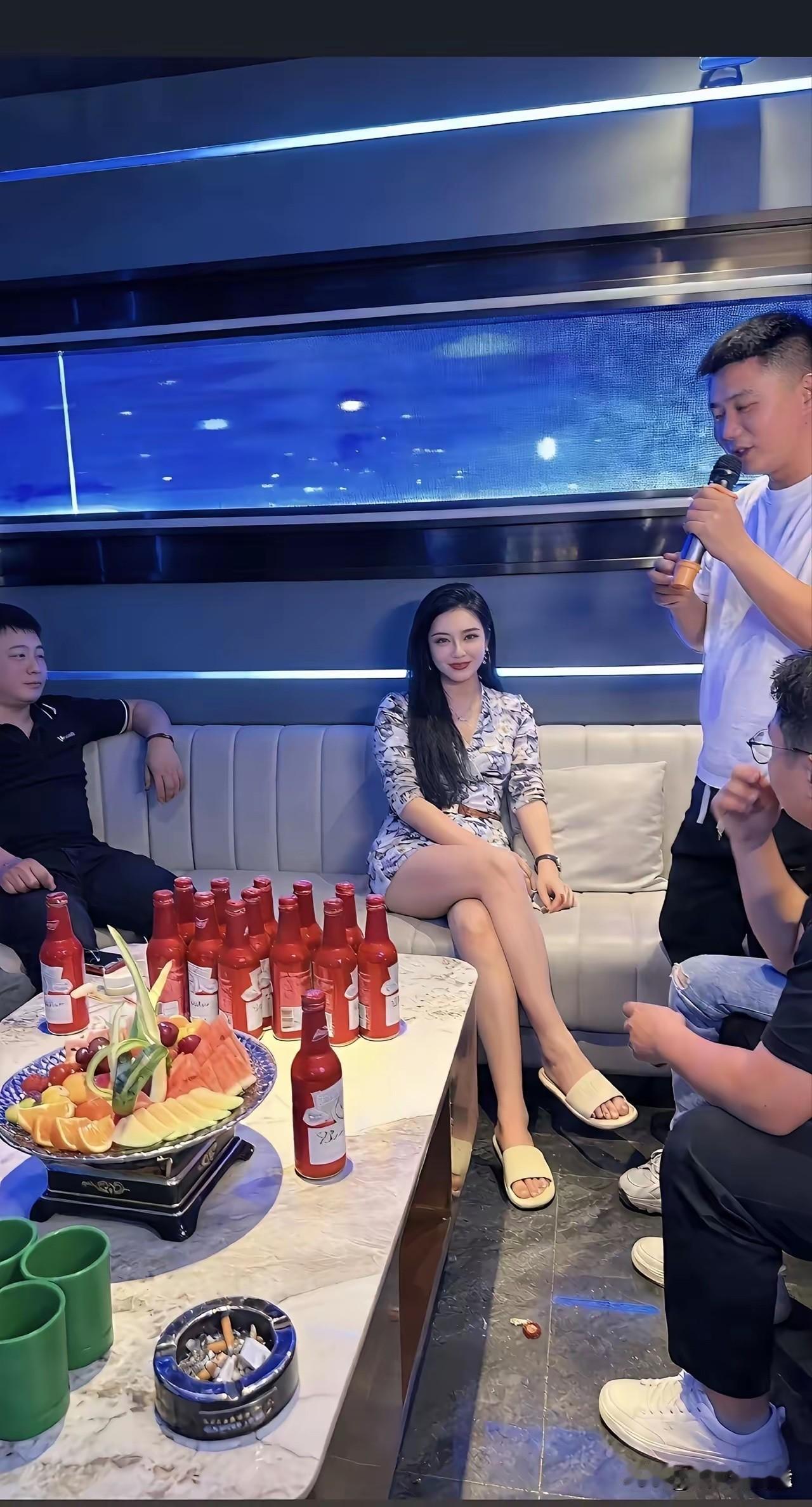 包厢里几位男士结伴唱歌，中间这位女生是朋友还是专门请来的？KTV包厢里摆满酒水