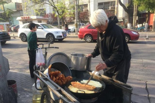 凌晨收摊的煎饼摊大爷，每天都会留最后一个饼，放在巷口垃圾桶盖上。邻居笑他：“穷