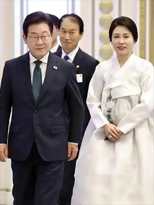 在温馨的场景中，李在明夫妇面带和蔼笑容，与前来献花的小朋友亲切互动。小朋友眼神纯