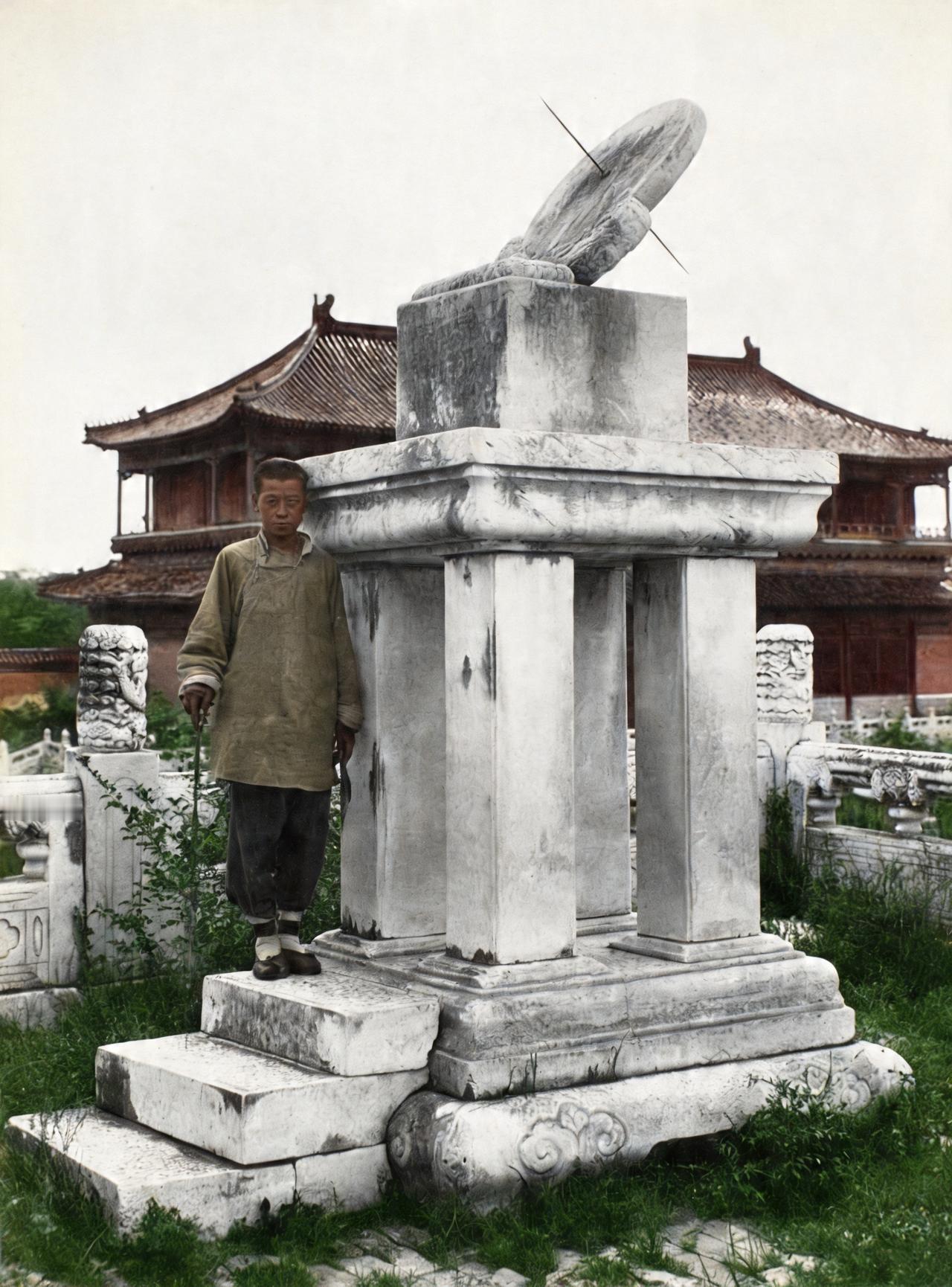 这是晚清一名男子站在太和殿前的日晷旁。紫禁城内杂草丛生、破旧不堪，毫无皇家建筑的