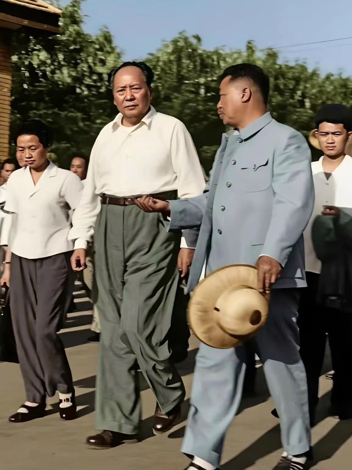 毛主席与贺龙元帅同行视察的照片，路上贺龙手持草帽，侧过身子，认真向主席汇报基层情
