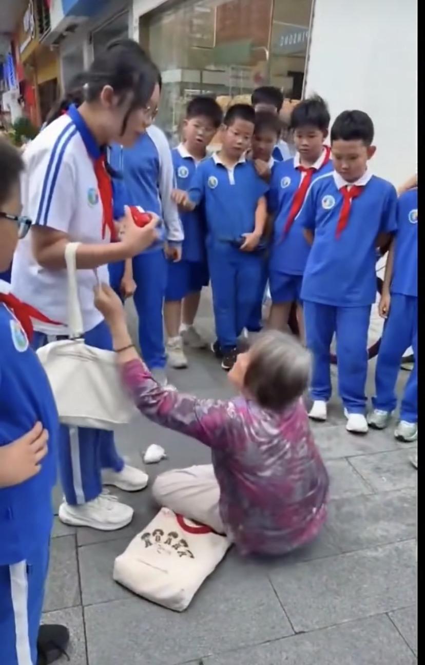 监控画面显示：老人摔倒后，一群小学生路过，一位女生见状，立即扶起老人，没想到老人