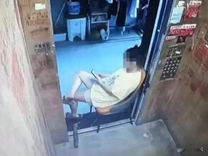 离谱至极！广东一名女子为蹭电梯空调，搬凳子卡住电梯门缝，翘着二郎腿久坐刷手机，导