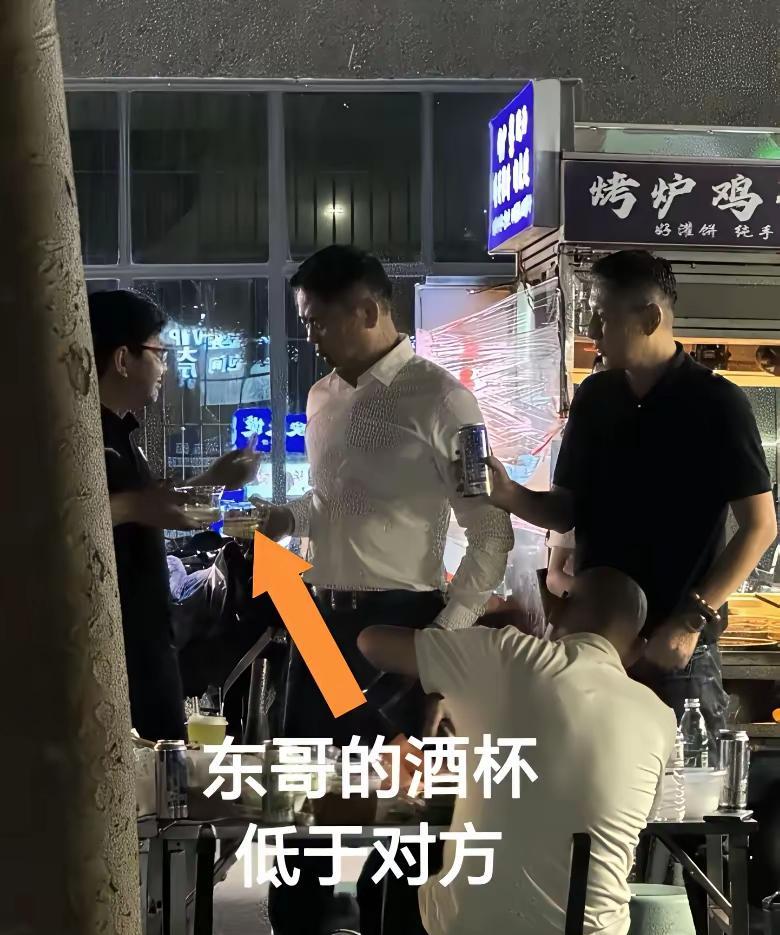 注意看刘强东在家乡宿迁地摊吃饭，与也是在地摊吃饭的陌生人一块碰杯喝酒的时候，他把